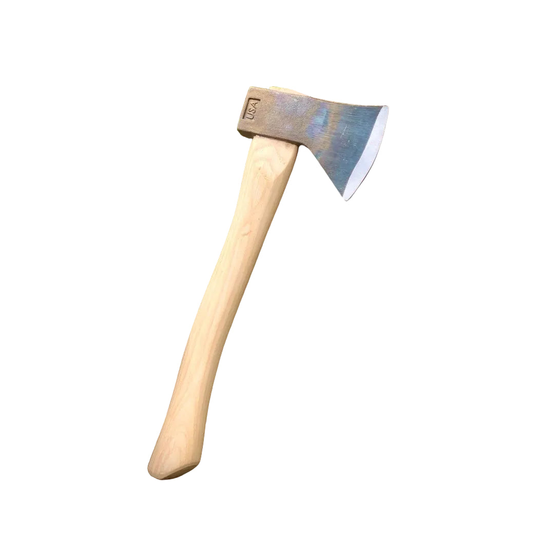 A natural wood-handled Council Tool Co. Hudson Bay Camp Axe rests on stacked rocks with green grass in the background.