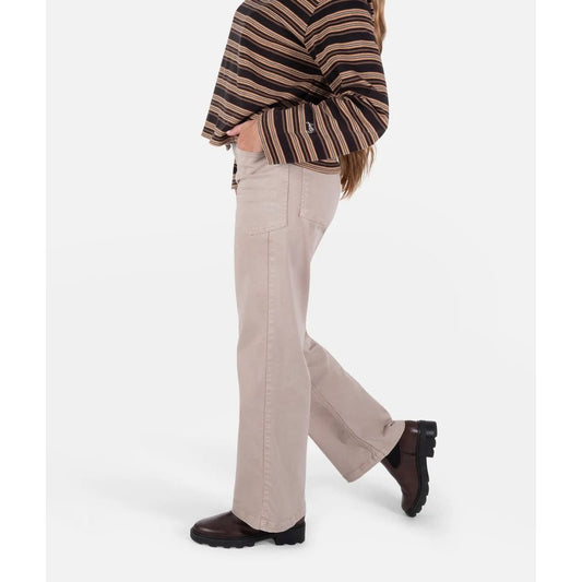 Side view of the Jetty Womens Lilah Pant in Tan showing a model wearing it with a striped top and dark shoes against a white background.