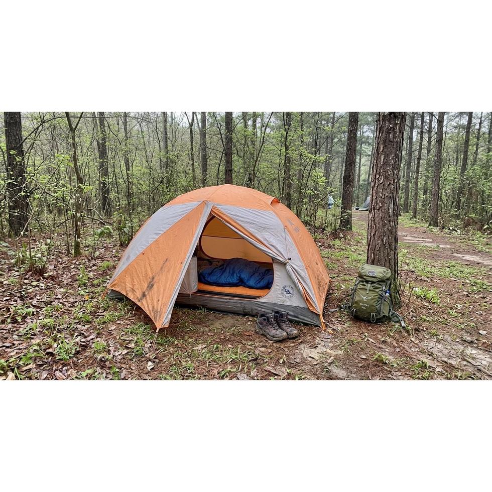 Camper using a spring sleeping bag outside a tent on a cool morning