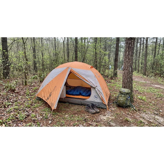 Camper using a spring sleeping bag outside a tent on a cool morning
