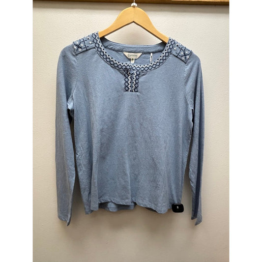 Front view of the Aventura Women's Bronte Top in Faded Demin hanging on a wooden hanger against a plain wall.
