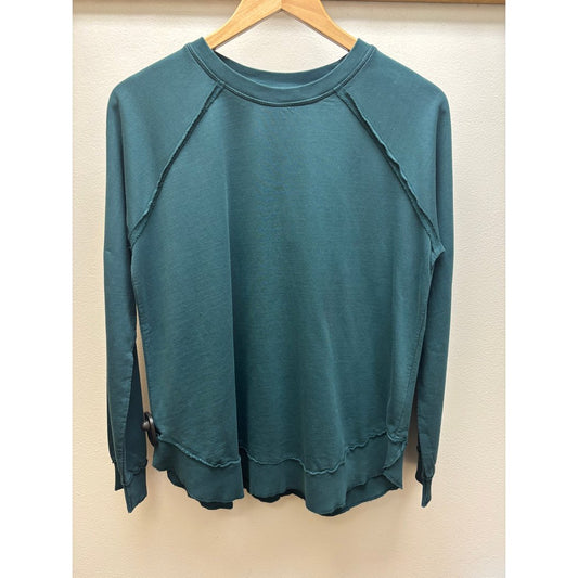 Front view of the Aventura Women's Cotton Drift Crew Neck in Reflecting Pond hanging on a wooden hanger against a beige wall.