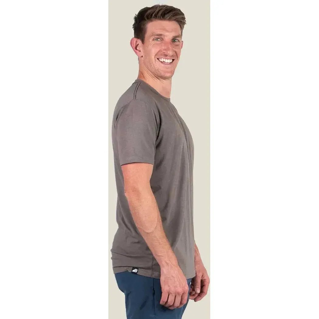 Side view of the Belong Designs Men's Core Traverse Tek Tee in Granite showing the model wearing it against a light background.