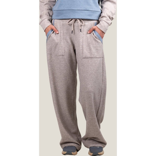 Front view of the Belong Designs Women's Powell Fleece Pant in Beige with hands in pockets and a model wearing it.