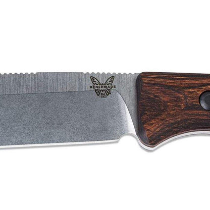 A close-up of the Benchmade 15002 Saddle Mountain Skinner knife with a dark wood handle and serrated edge, photographed against a white background.