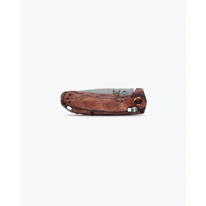 A side view of the Benchmade North Fork in Maple Stabilized Wood with a serrated blade and a wooden handle against a white background.
