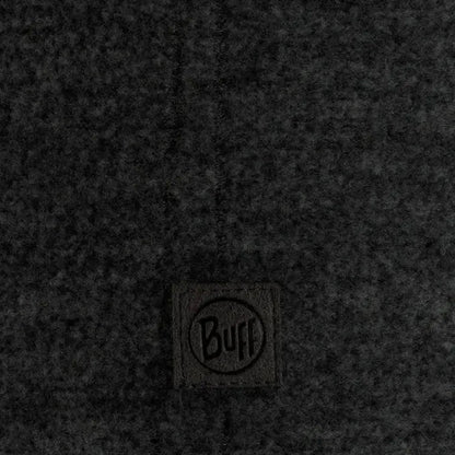 A close-up of the Buff Merino Fleece Headband Vente Prive in Black showing the brand tag on a dark fabric background.