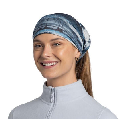 A woman wears the Blue Buff Original EcoStretch - Oser headband with a ponytail, against a plain white background.