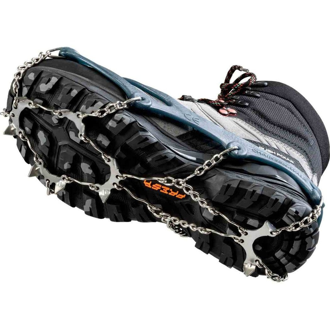 Close-up of the CAMP Spikes Walk attached to a black hiking boot showing metal chains and spikes on the sole.