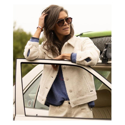A woman in a Birch Carve Designs Women's Rhea Boucle Trucker jacket leans on a white car door with a green roof rack.