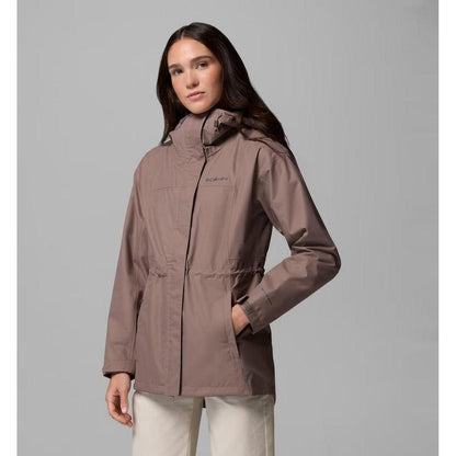 A woman models the Columbia Sportswear Women's Hikebound II Long Jacket in Iron, showing the front with a high collar and pockets, against a plain gray background.