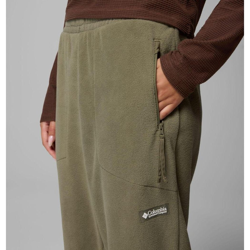 Side view of the Columbia Sportswear Women's Sequoia Grove Fleece Pants in Stone Green showing the zippered pocket and model wearing them against a gray background.
