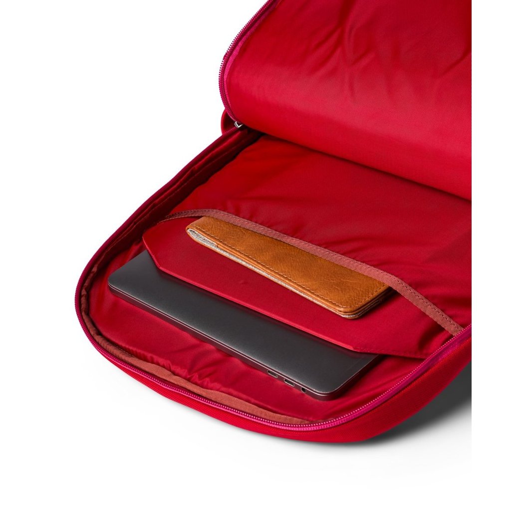 Open view of the Cotopaxi Allpa 26L Daypack in Blue Spruce/Abyss showing its red-lined interior with a laptop and wallet inside.