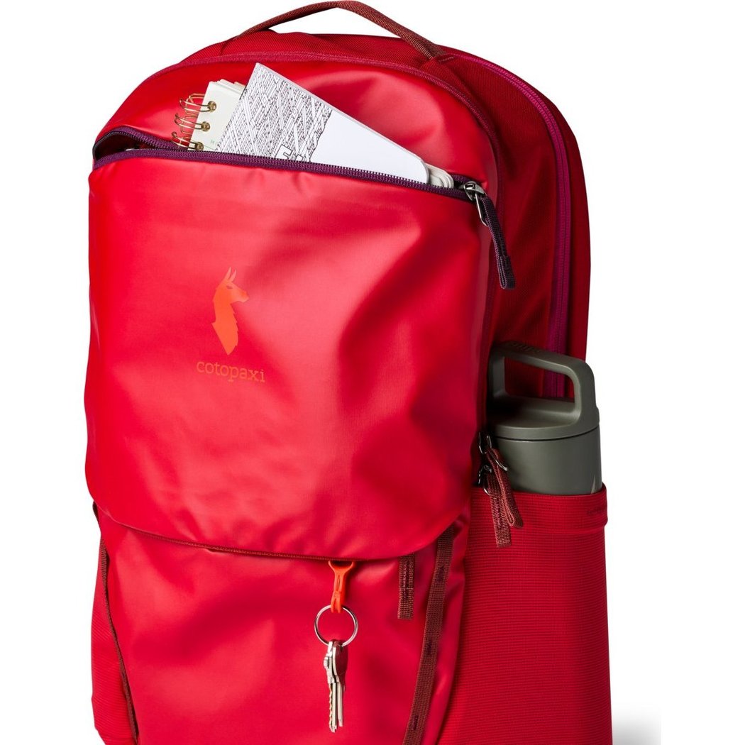 Front view of the Cotopaxi Allpa 26L Daypack in Blue Spruce/Abyss with a notebook and water bottle visible.