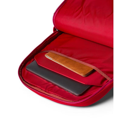 Open view of the Cotopaxi Allpa 26L Daypack in Blue Spruce/Abyss showing its red-lined interior with a laptop and wallet inside.