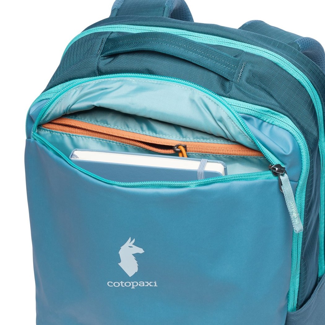 Front view of the Cotopaxi Allpa 26L Daypack in Blue Spruce/Abyss showing the open front pocket with a tablet inside.