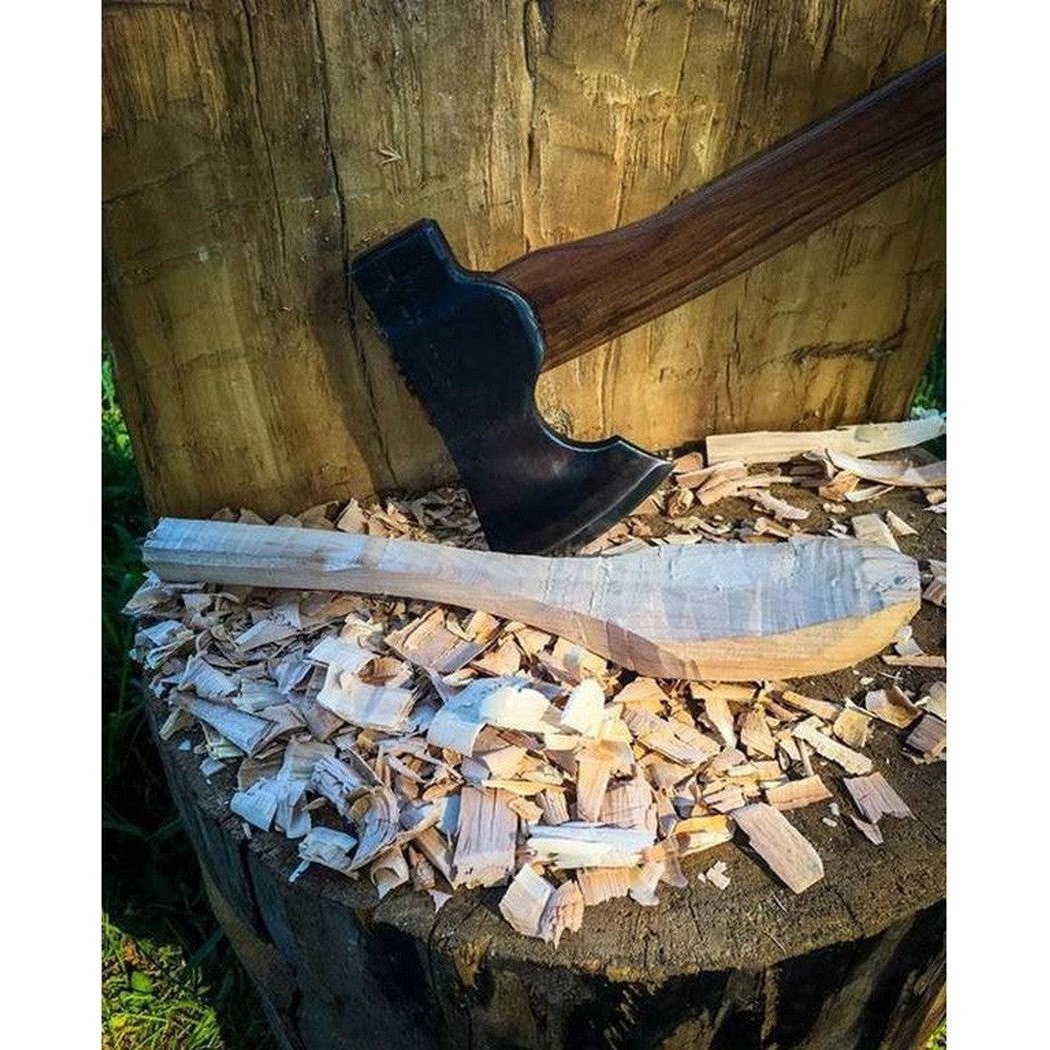 A 16" handle Council Tool Co. Wood-Craft Camp Carver axe rests on wood shavings atop a tree stump.