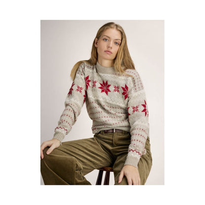 A model wearing the Dale Of Norway Egersund Fem. Sweater-SAMPLE in SandMelOffWhtRe sits on a stool against a plain background.