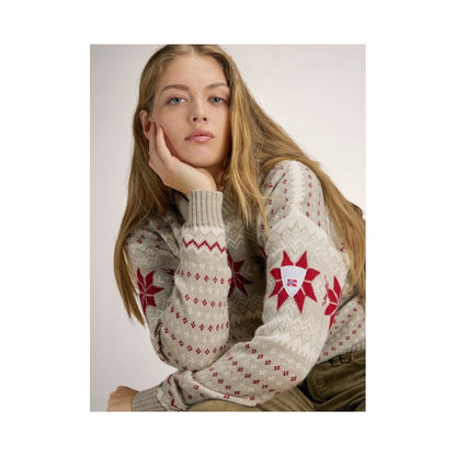 A model wearing the Dale Of Norway Egersund Fem. Sweater-SAMPLE in SandMelOffWhtRe poses with her hand on her face against a light background.