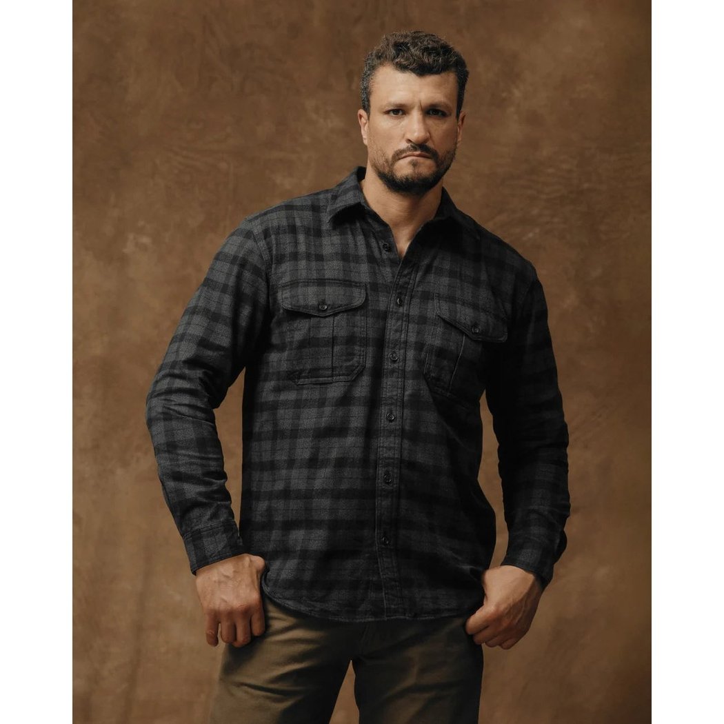 Front view of the Filson Men's Alaskan Guide Shirt in Heath Blk Plaid with a model wearing it against a brown background.