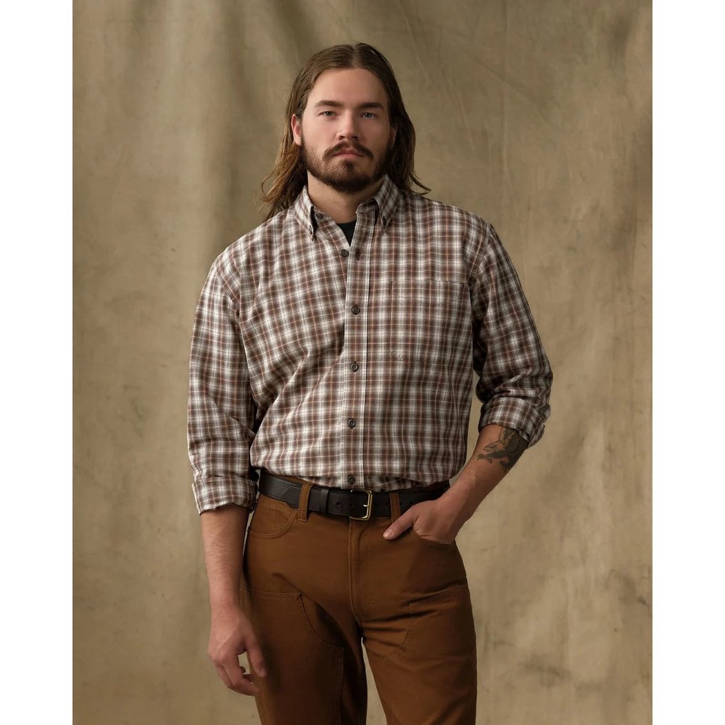 Front view of the Filson Men's Chambray Button-Down Shirt in Cascade PLaid with a model wearing it against a tan backdrop.