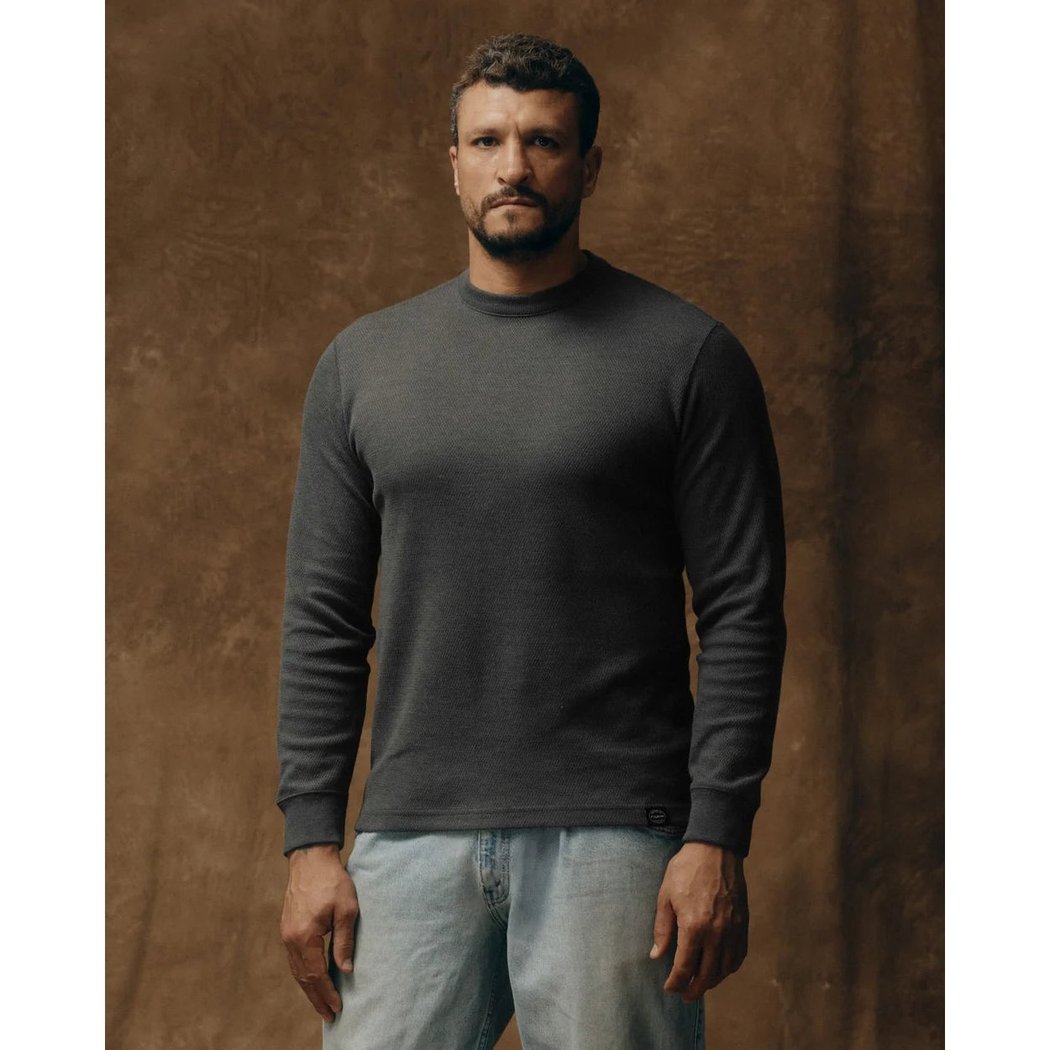 Front view of the Filson Men's Waffle Knit Thermal Crewneck in Charcoal on a man against a brown background.
