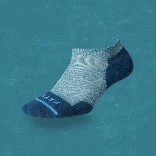 A side view of the FITS Light Runner Low socks in Juno color against a teal background.