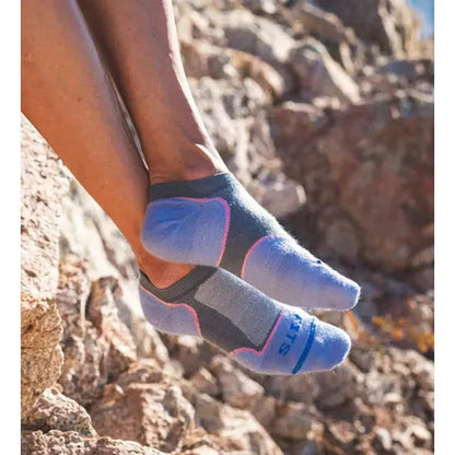 A woman’s feet in Stormy Weather FITS Women's Ultra Light Runner No Show socks, showing the toe and heel design against a rocky outdoor background.