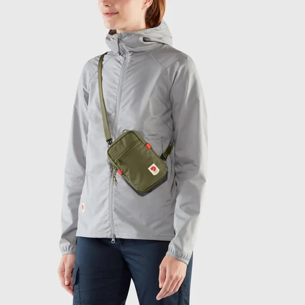 Side view of the Fjallraven High Coast Pocket in Black on a model wearing a gray jacket against a plain background.