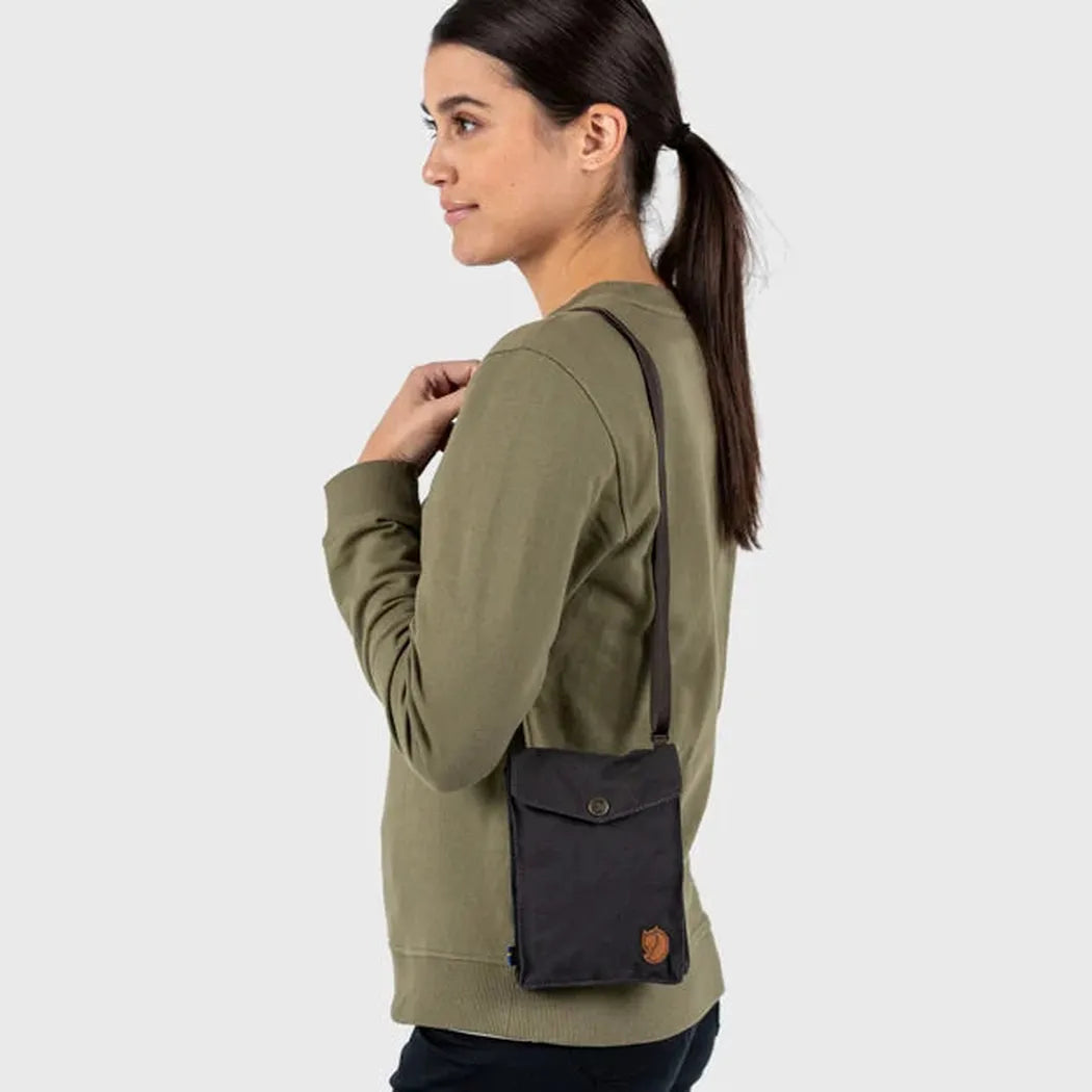 Side view of the Fjallraven Pocket in Black on a model against a plain white background.