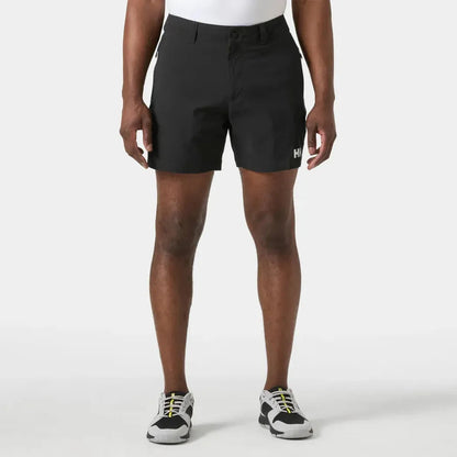 A front view of the Helly Hansen Men's Move Quick Dry 6” Shorts in Black on a model wearing white sneakers against a plain white background.