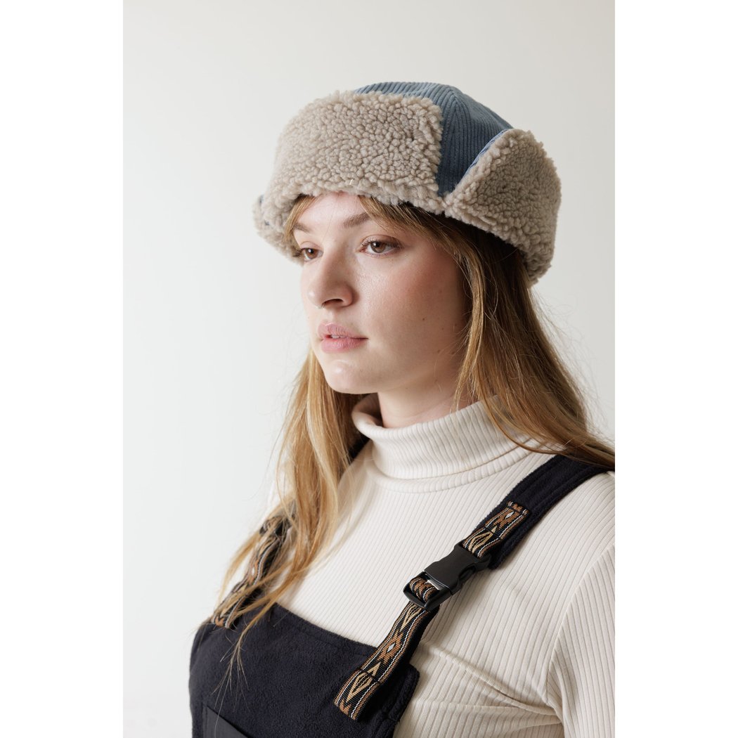 Side view of the Kavu Fur Ball Fudd in Moonless Night on a model with a white turtleneck and dark overalls against a plain background.