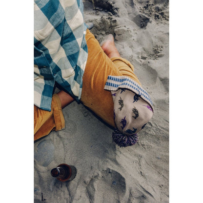 Top-down view of the Kavu Herschel in Squirrely on a sandy beach with a bottle nearby.