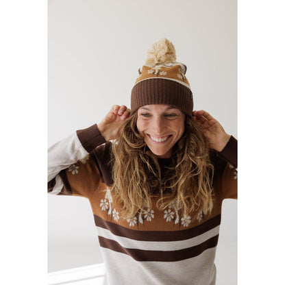 Woman wearing the Kavu Hillrose in Forage Patch adjusts the hat against a white background.