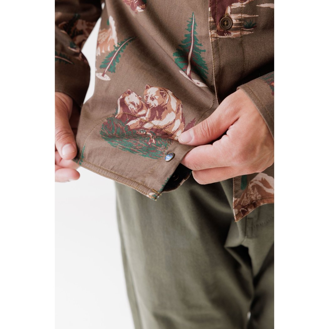 Close-up of the Kavu Westerly in Faraway Forest showing a bear print and a model adjusting the shirt.