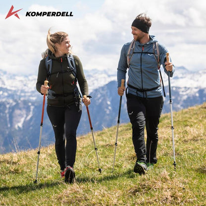 Komperdell Ridgehiker Zero Compact trekking poles in use by two hikers on a grassy mountain slope with snow-capped peaks in the background.
