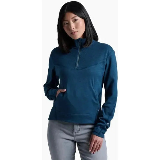 A front view of the Kuhl Women's Lola 1/2 Zip in Metal Blue on a model wearing light gray pants against a white background.