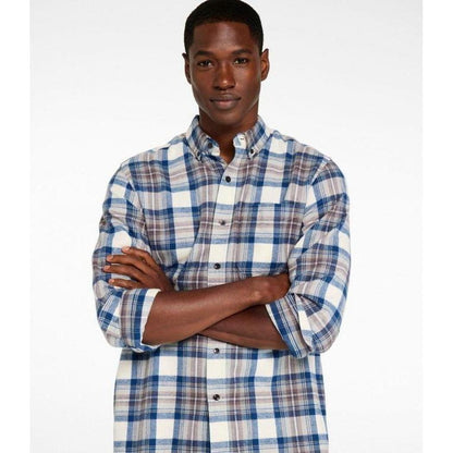 A model wearing the L.L.Bean Men's Long Sleeve Scotch Plaid Flannel Shirt in Indigo Tartan stands with arms crossed against a plain white background.