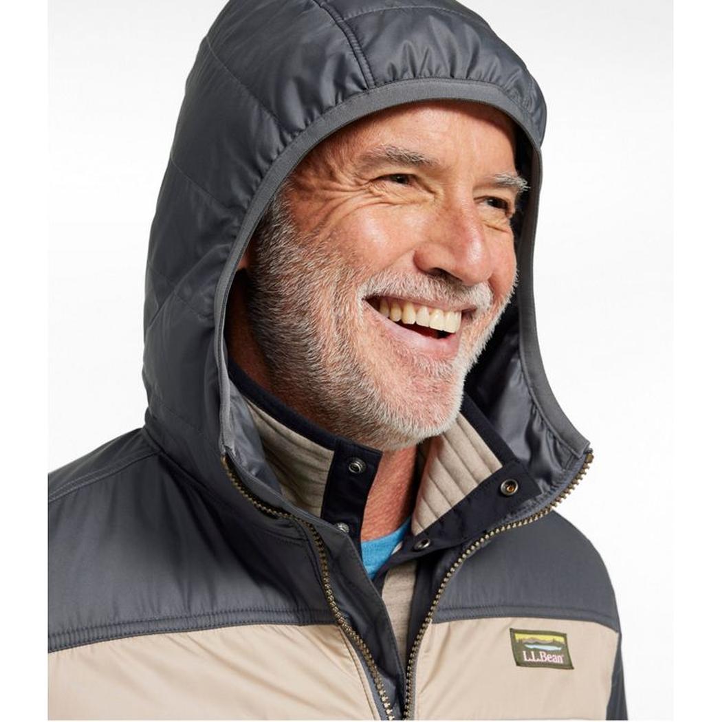 A man smiles wearing the L.L.Bean Men's Mountain Classic Colorblock Puffer Hooded Jacket in Iron/Putty against a white background.
