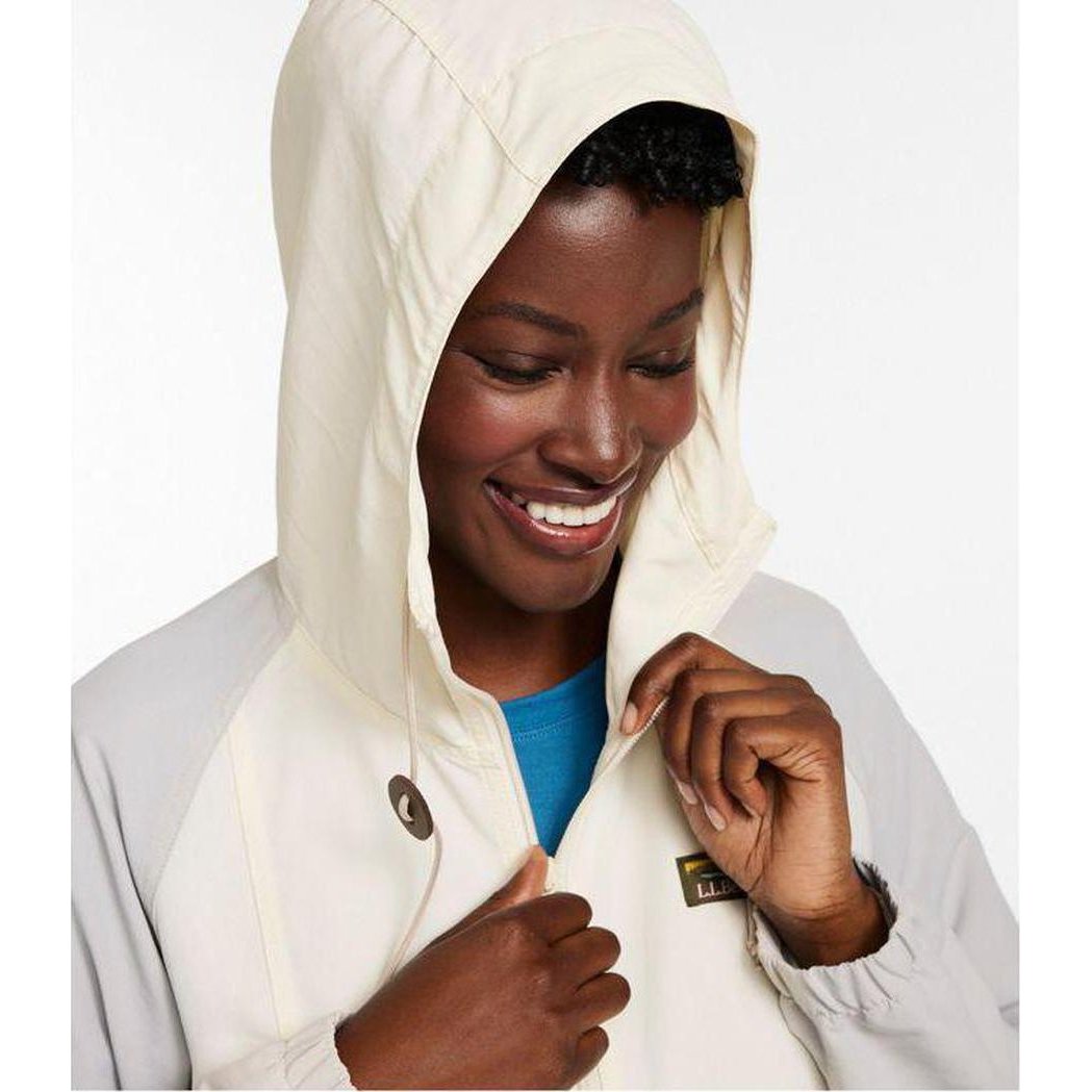 A woman wears the L.L.Bean Women's Mountain Classic Anorak in Paperwhite/Putty, adjusting the hood against a plain white background.