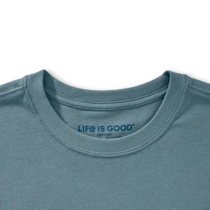 A close-up of the Life is Good Men's Free Hugs Shark Short Sleeve Crusher-LITE Tee in Slate Blue showing the collar and tag against a white background.