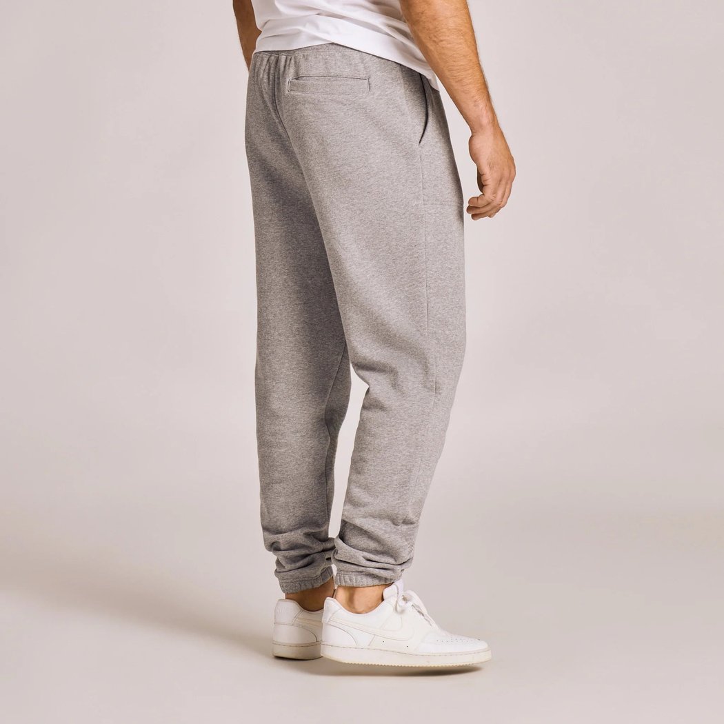 Side view of the Life is Good Men's Solid Good Vibes Jogger in Heather Gray showing the elastic cuffs and white sneakers against a light background.