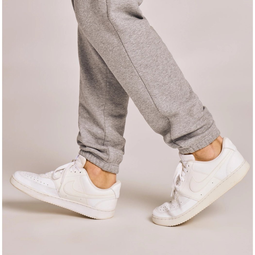 A model wearing Life is Good Men's Solid Good Vibes Joggers in Heather Gray with white sneakers against a light background.