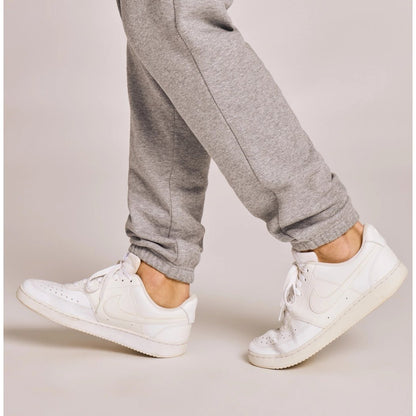A model wearing Life is Good Men's Solid Good Vibes Joggers in Heather Gray with white sneakers against a light background.