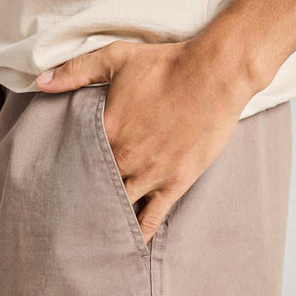 A hand in the pocket of the Life is Good Men's Solid Weekender Short in Mushroom Brown, showing the side seam and pocket detail.