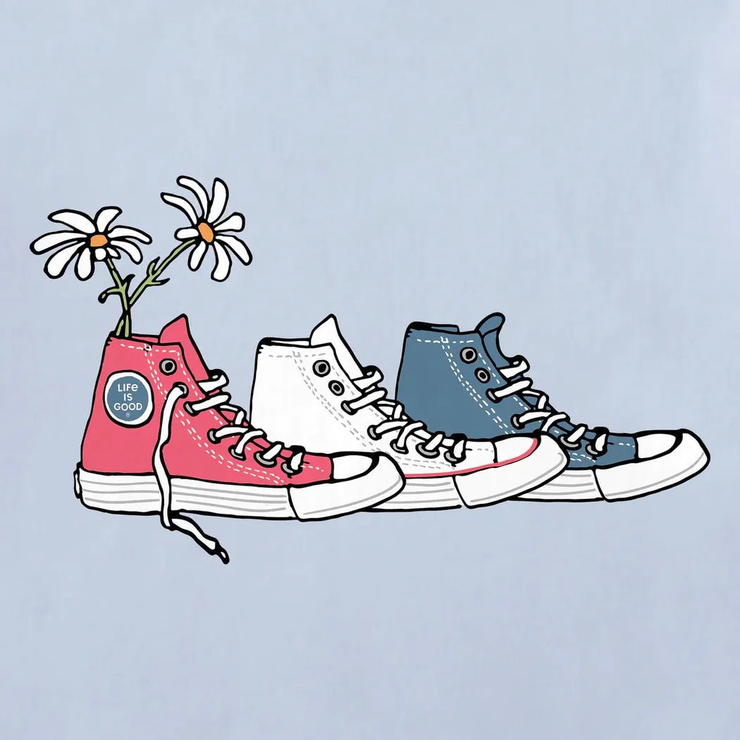 A front view of the Life is Good Women's Patriotic Daisy Sneakers Short Sleeve Tee in Glacier Blue with a light blue background.