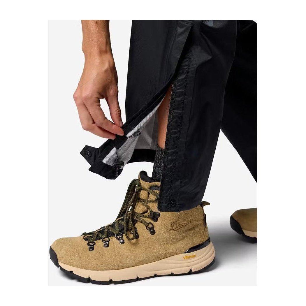 A person shows the inner lining of the Marmot Women's PreCip Evo Pant in Black while wearing a tan hiking boot.