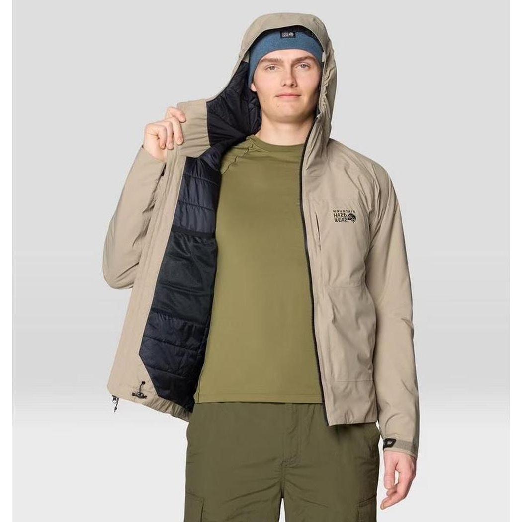 A model wears the Mountain Hardwear Men's Stretch Ozonic Insulated Jacket in Dunes, showing the hood and insulated lining against a light background.