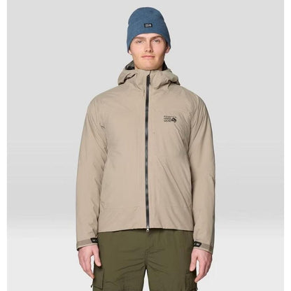 A front view of the Mountain Hardwear Men's Stretch Ozonic Insulated Jacket in Dunes on a model wearing olive cargo pants and a blue beanie against a light gray background.