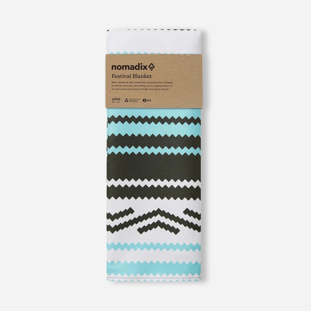 Front view of the Nomadix Festival Blanket in Baja Aqua with a brown label and geometric patterns against a white background.